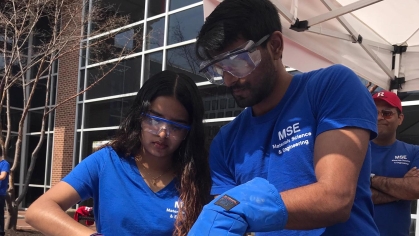 Two student wearing blue t-shirts making nitgogen ice cream outdoors.