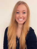 Head shot of smiling female with long blond hair wearing a black sweater.