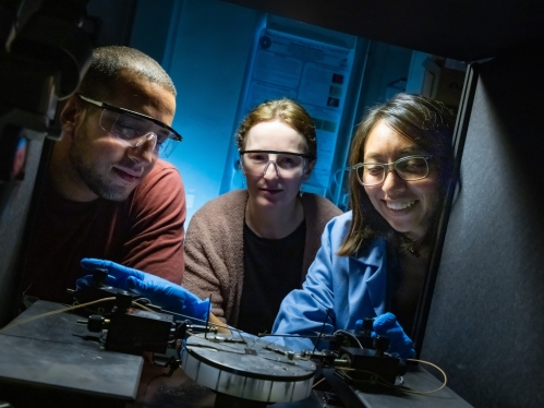 In the center of the photo, a female professor instructs a female student and a male student in her lab. 