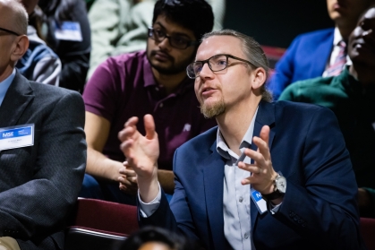 White male with glasses is speaking in using hand gestures.